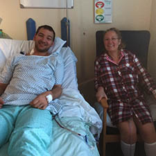 Chris lying in bed in hospital, smiling