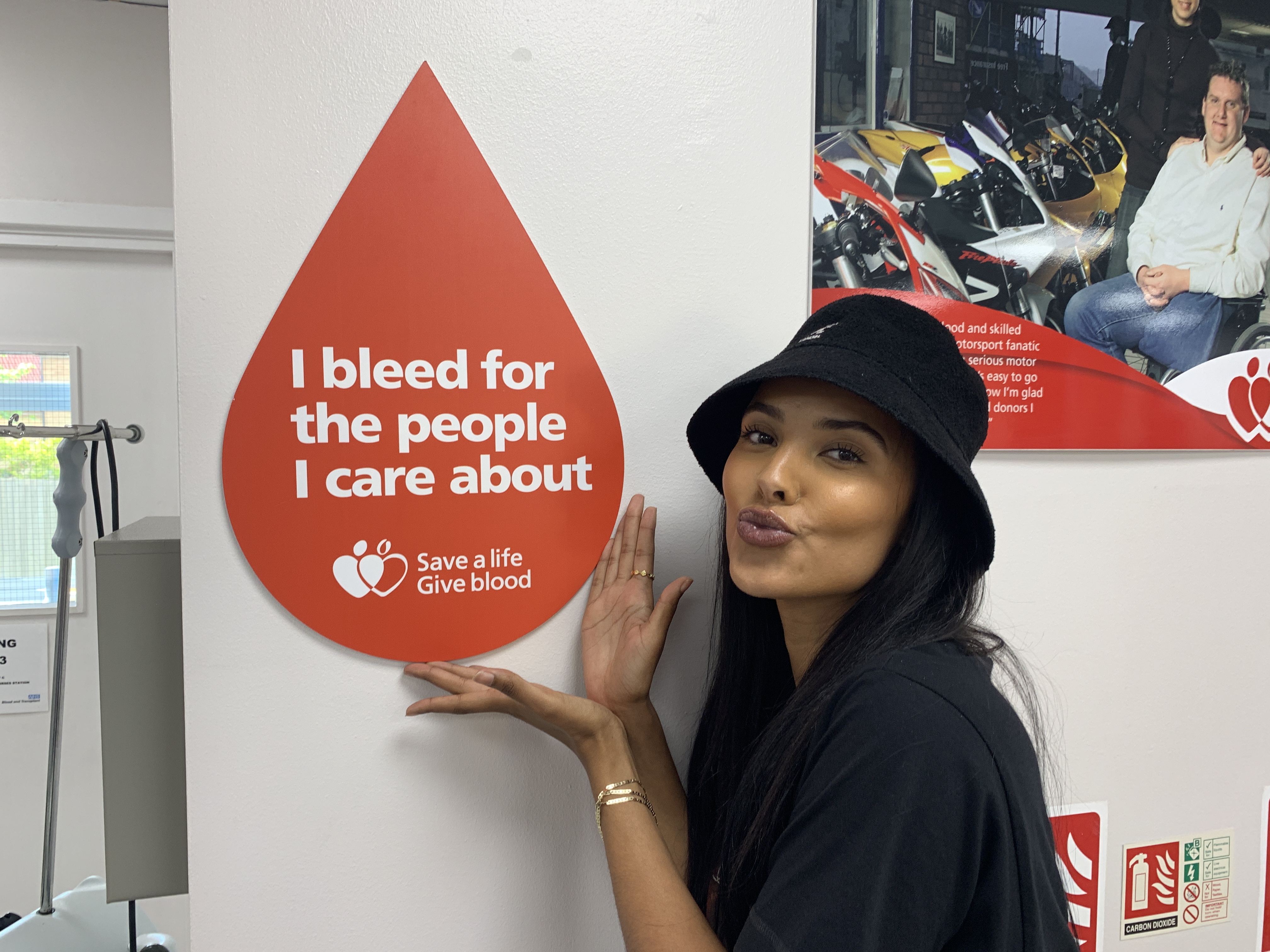 Maya Jama with a poses with a giant blood drop poster