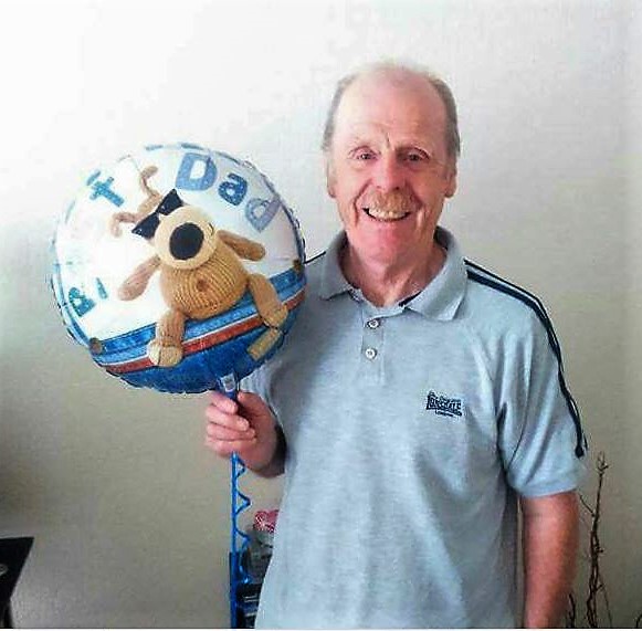 William holding a 'Best Dad' balloon and smiling