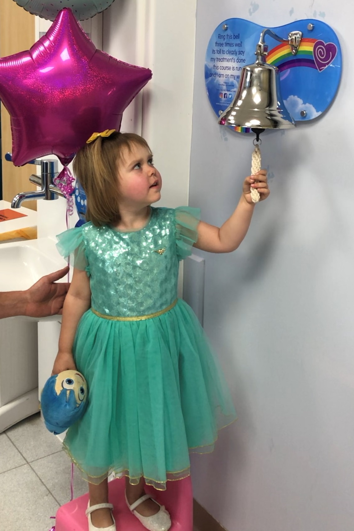 Sophia rings a silver bell that's mounted on a wall