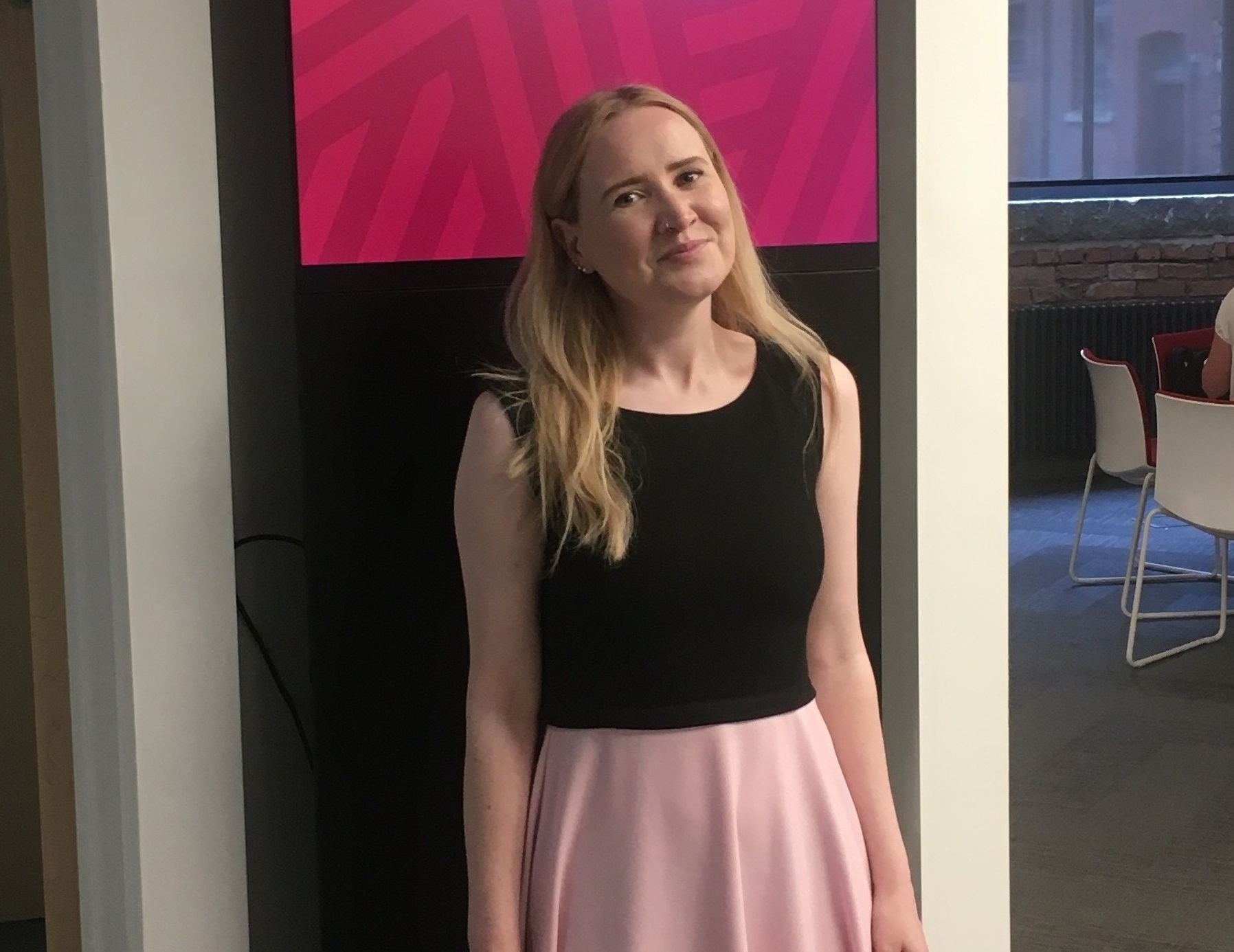 Laura smiling for a photo, in a black and pink dress