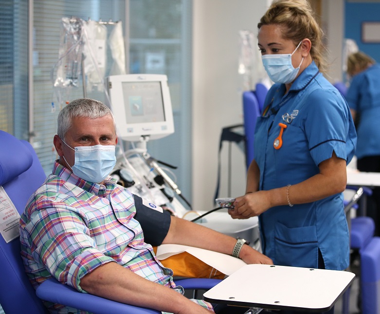 A man gives blood while wearing a face mask