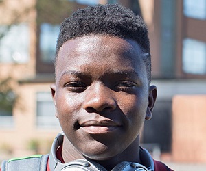 Black teenage boy with headphones smiling confidently