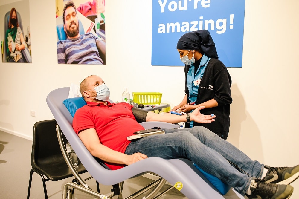 A blood donor talks to a donor carer while he donates