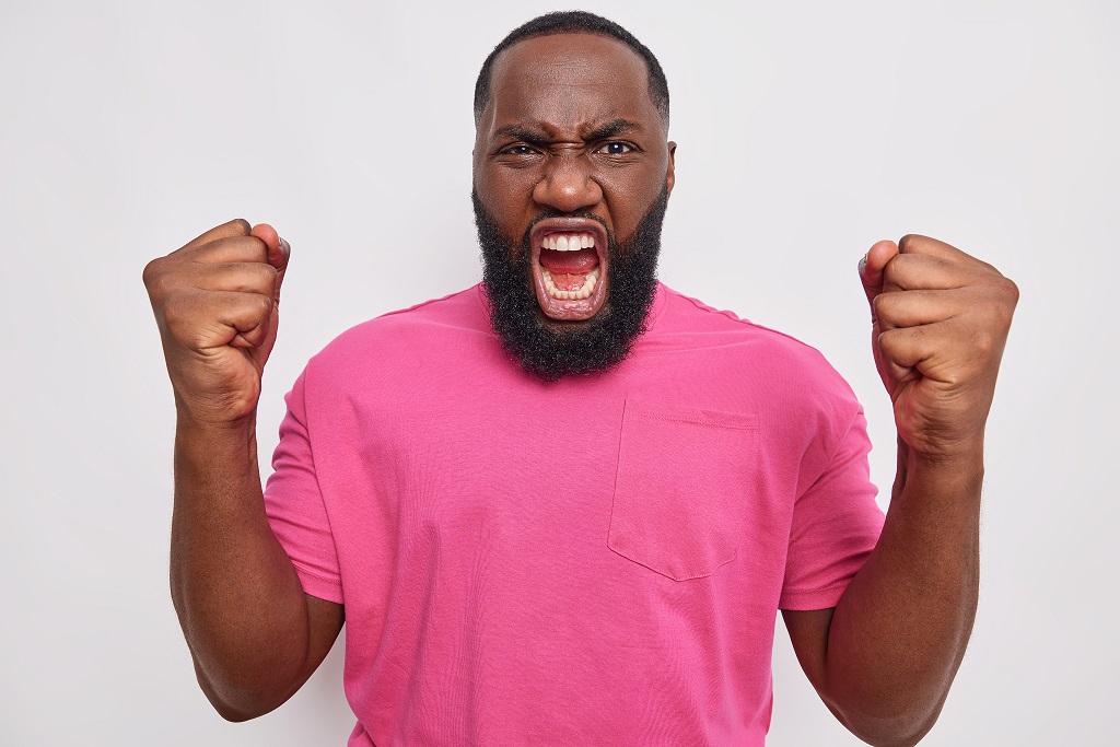 An excited-looking man in a pink t-shirt