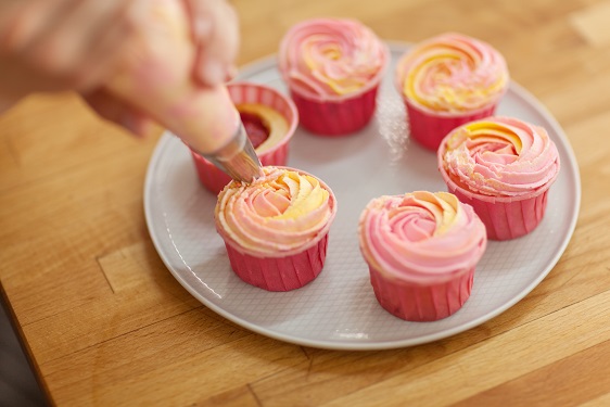 Piping pink icing onto cupcakes