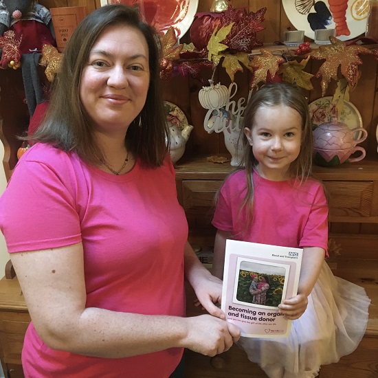 Katrina, a transplant recipient, wears pink alongside her daughter – Katrina is holding up an NHS Organ Donation information leaflet, which she features in.