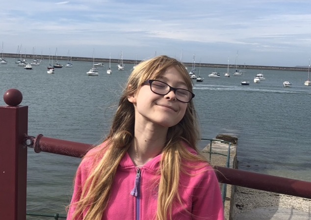 Angharad standing by a harbour, smiling
