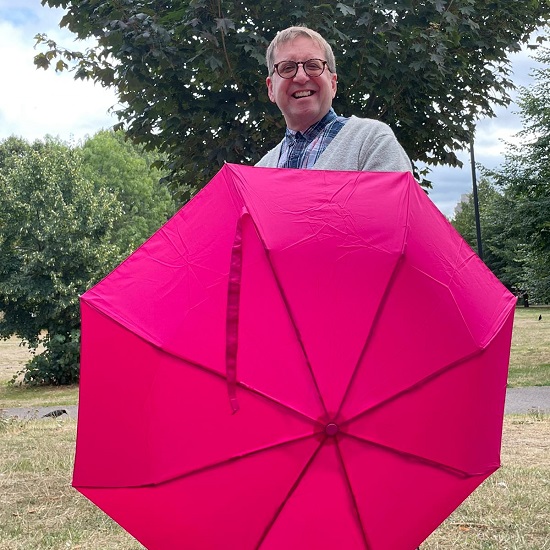 NHS Blood and Transplant ambassador and heart transplant recipient Andrew holds a pink umbrella