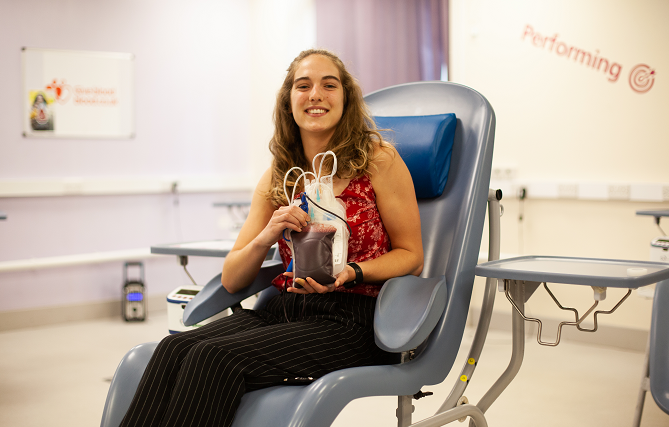 A blood donor holding her donation and smiling