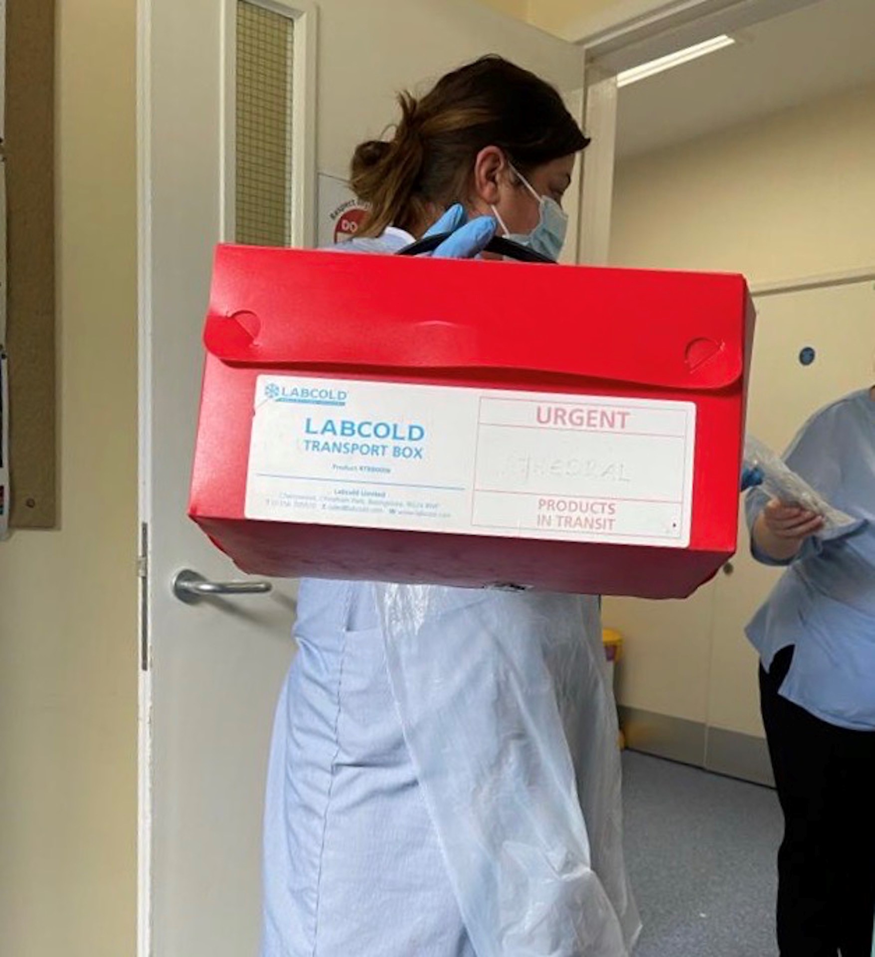A nurse carrying a box of blood products