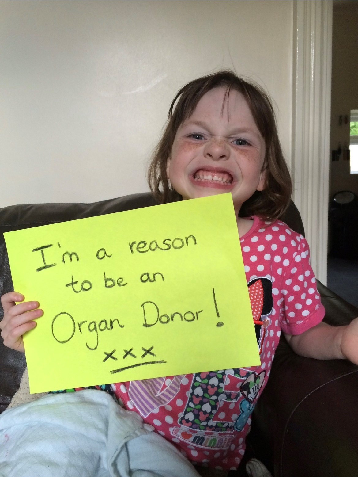 Young Ava holding a sign saying 'I'm a reason to be an organ donor!'