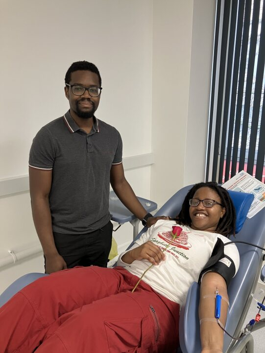 Kanika donating blood with her red rose, supported by boyfriend Idris at Birmingham donor centre