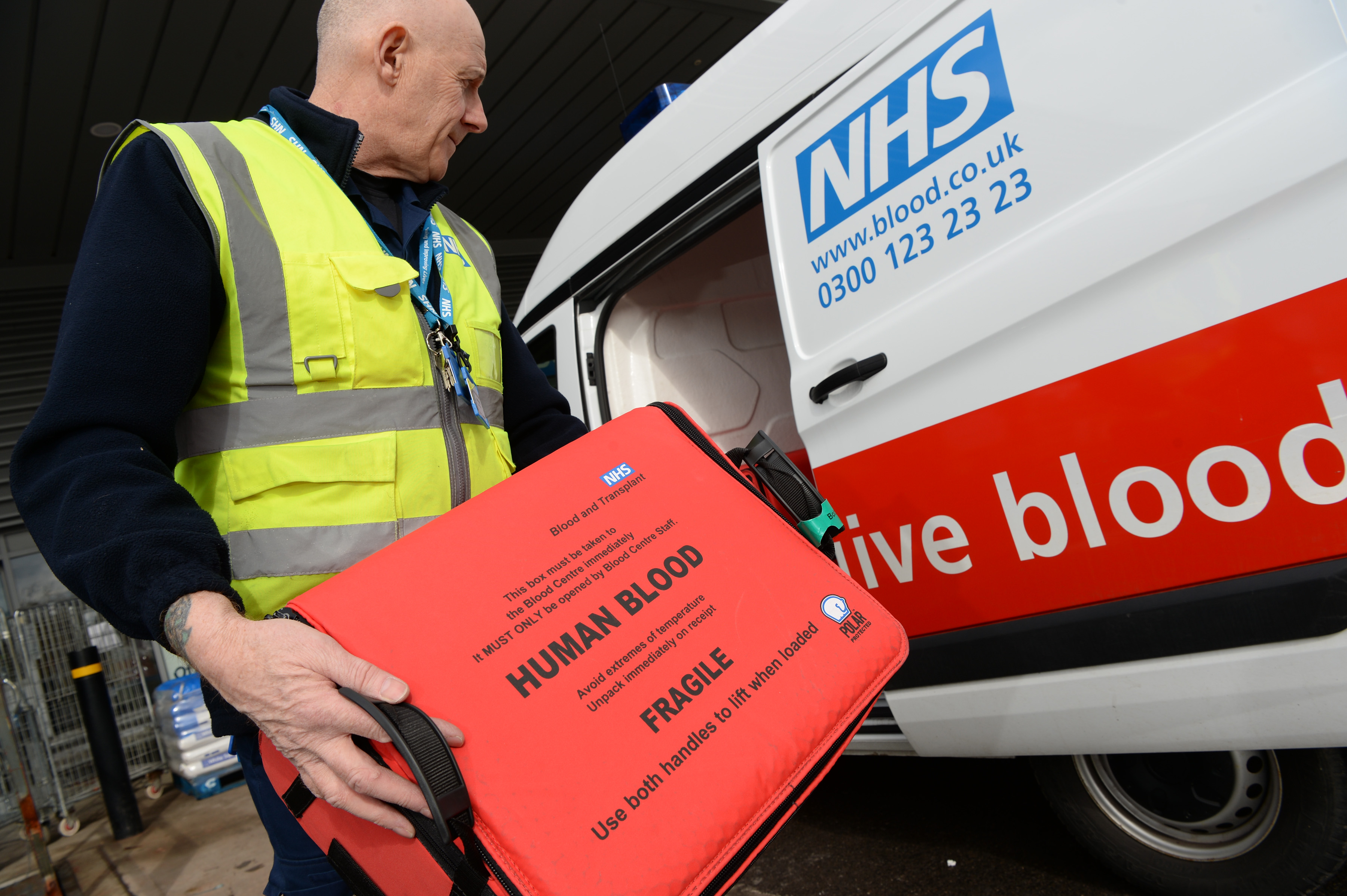 A member of NHSBT staff loading a case containing donated blood into a van