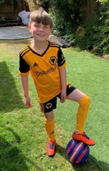 Oscar wearing his Wolves football kit and standing with a football