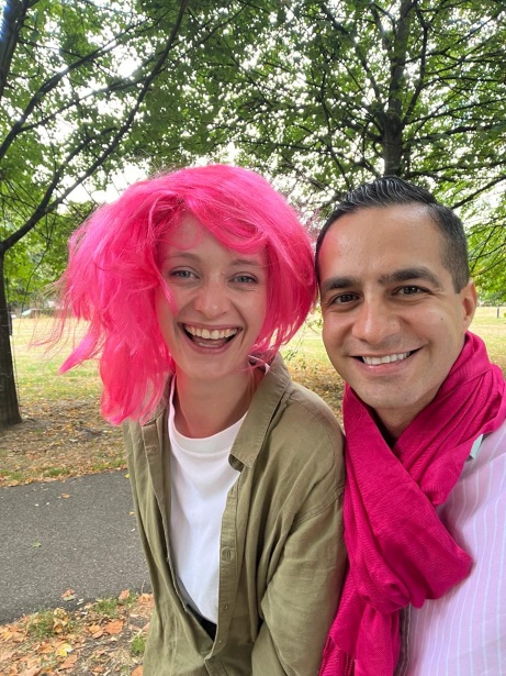 Two people, one with pink hair and one wearing a pink scarf