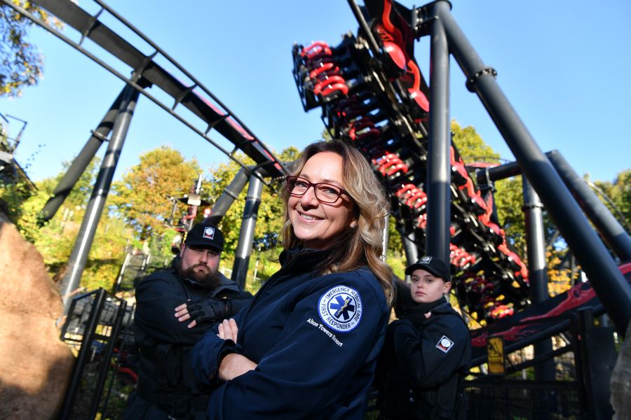 Three members of Alton Towers Resort staff standing next to a ride