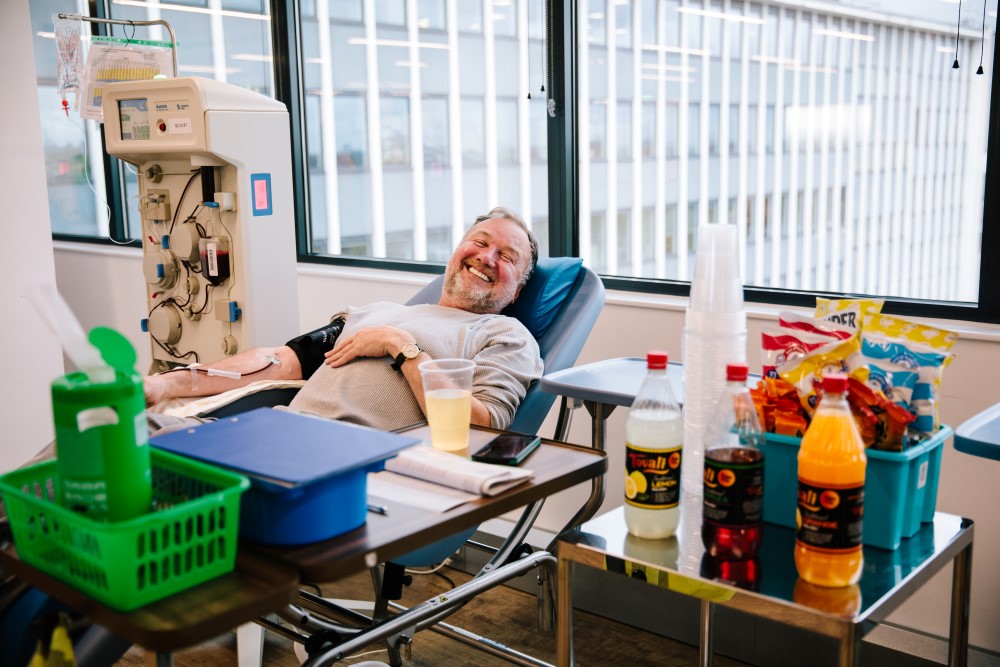 A donor smiling with drinks and snacks in the foreground