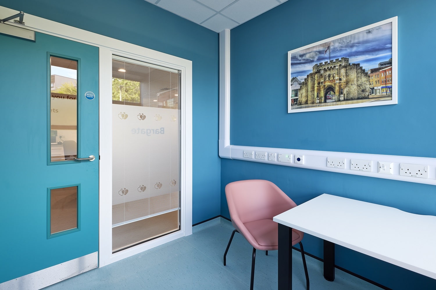 Welcoming looking consultation room, walls are pained sky blue with a picture of Bargate medieval gatehouse on the wall
