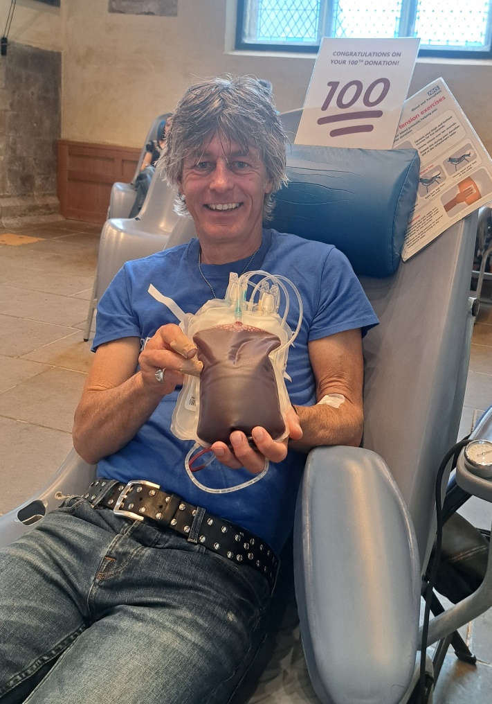 Robert Boocock holding a bag of donated blood, at his 100th donation session