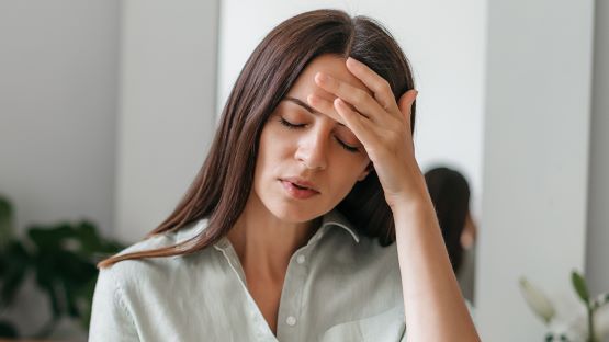 Woman holding her hand on her forehead with closed eyes