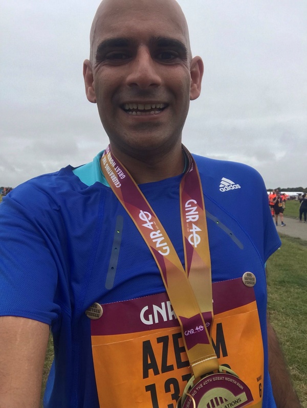Azeem Ahmad at a race event wearing a blue Adidas shirt and medals, post kidney donation.