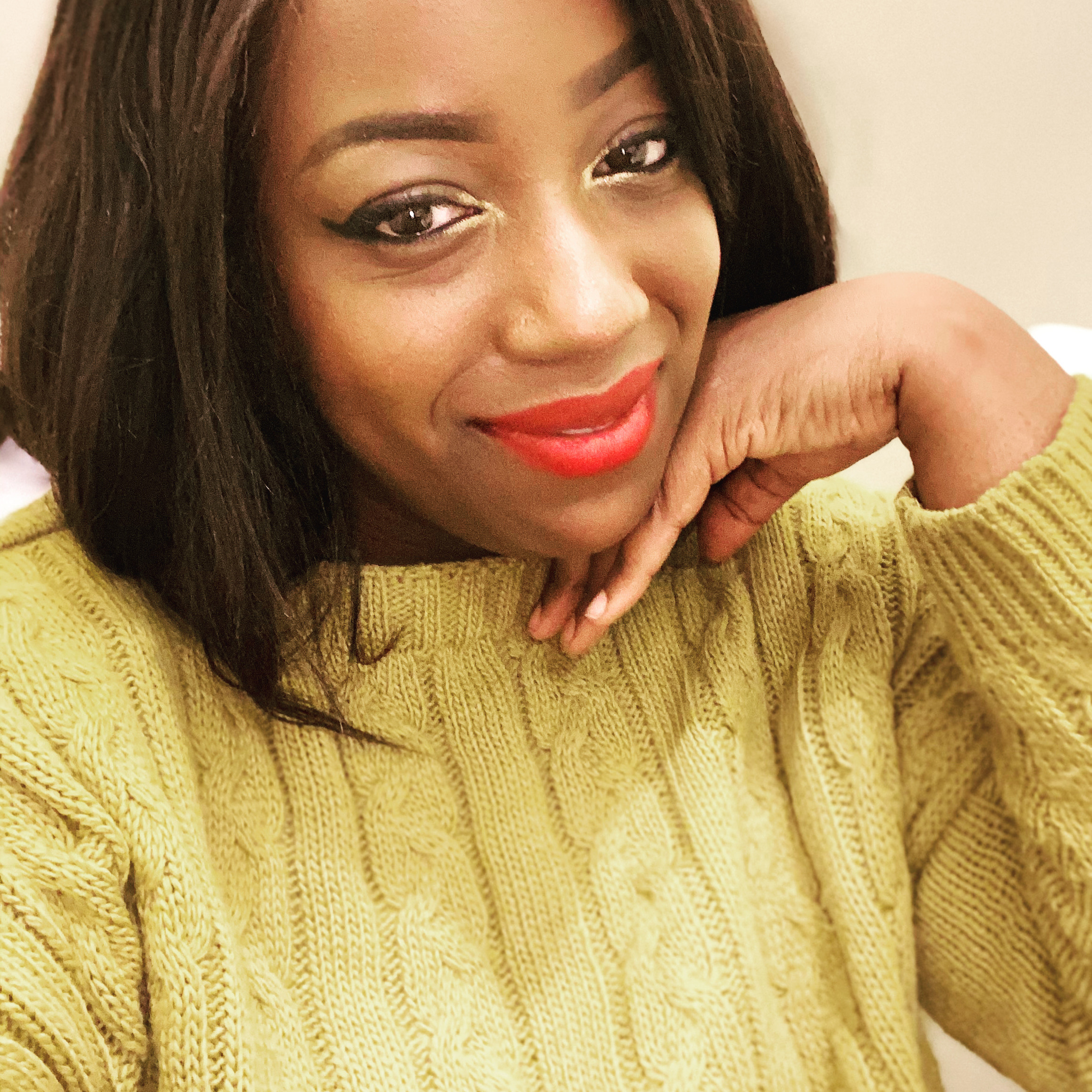 Illustrator Zenovia Grant wearing a light green sweater, resting her chin on her hand.