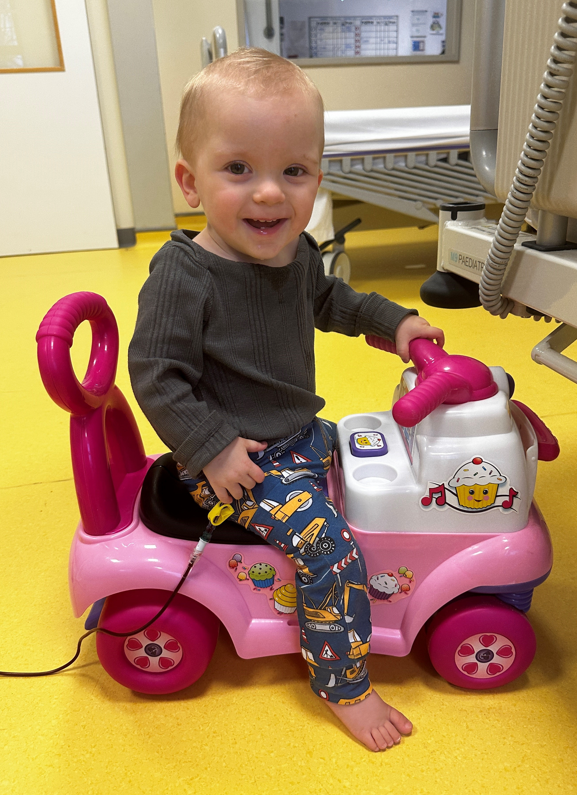 Woody smiling and playing on a toy scooter