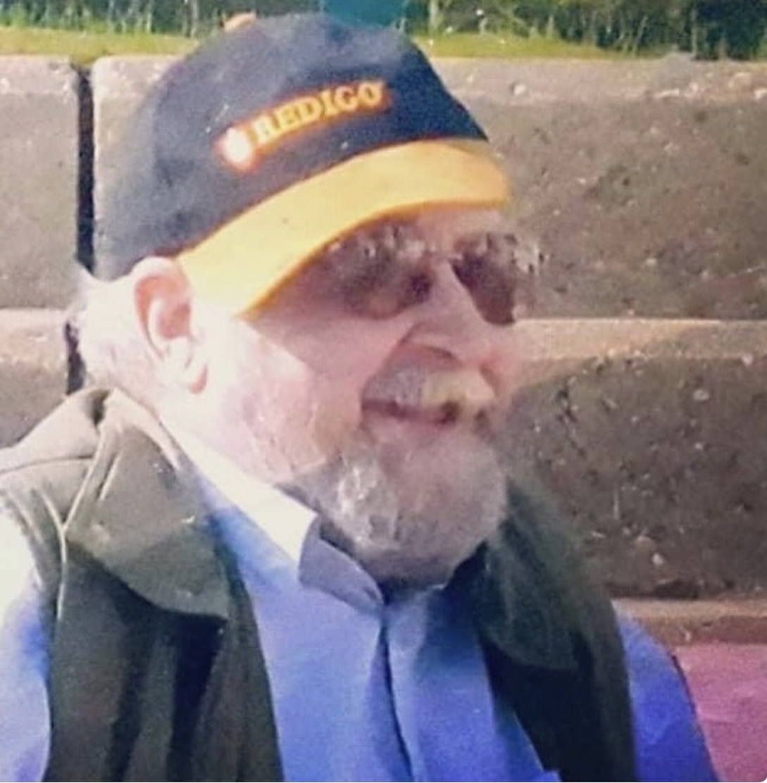 A picture of Ben's dad, named Ben, wearing a blue and yellow hat and glasses