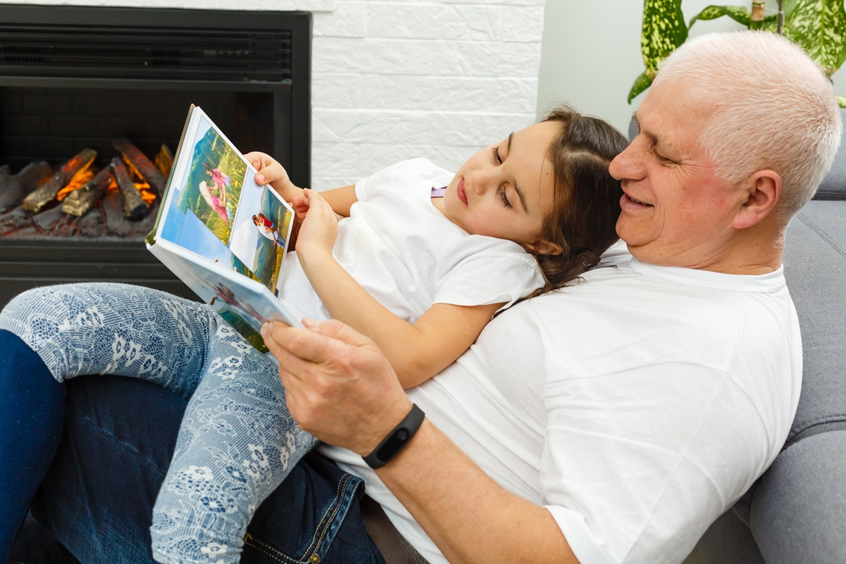 A young girl looking through photos with her grandfather