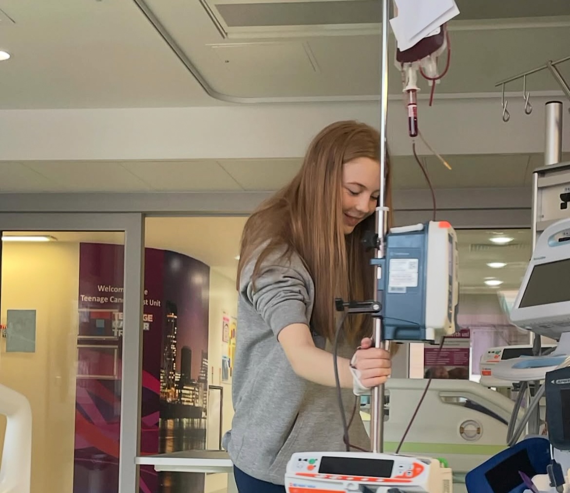 Maisie, standing with a medical stand during a blood transfusion