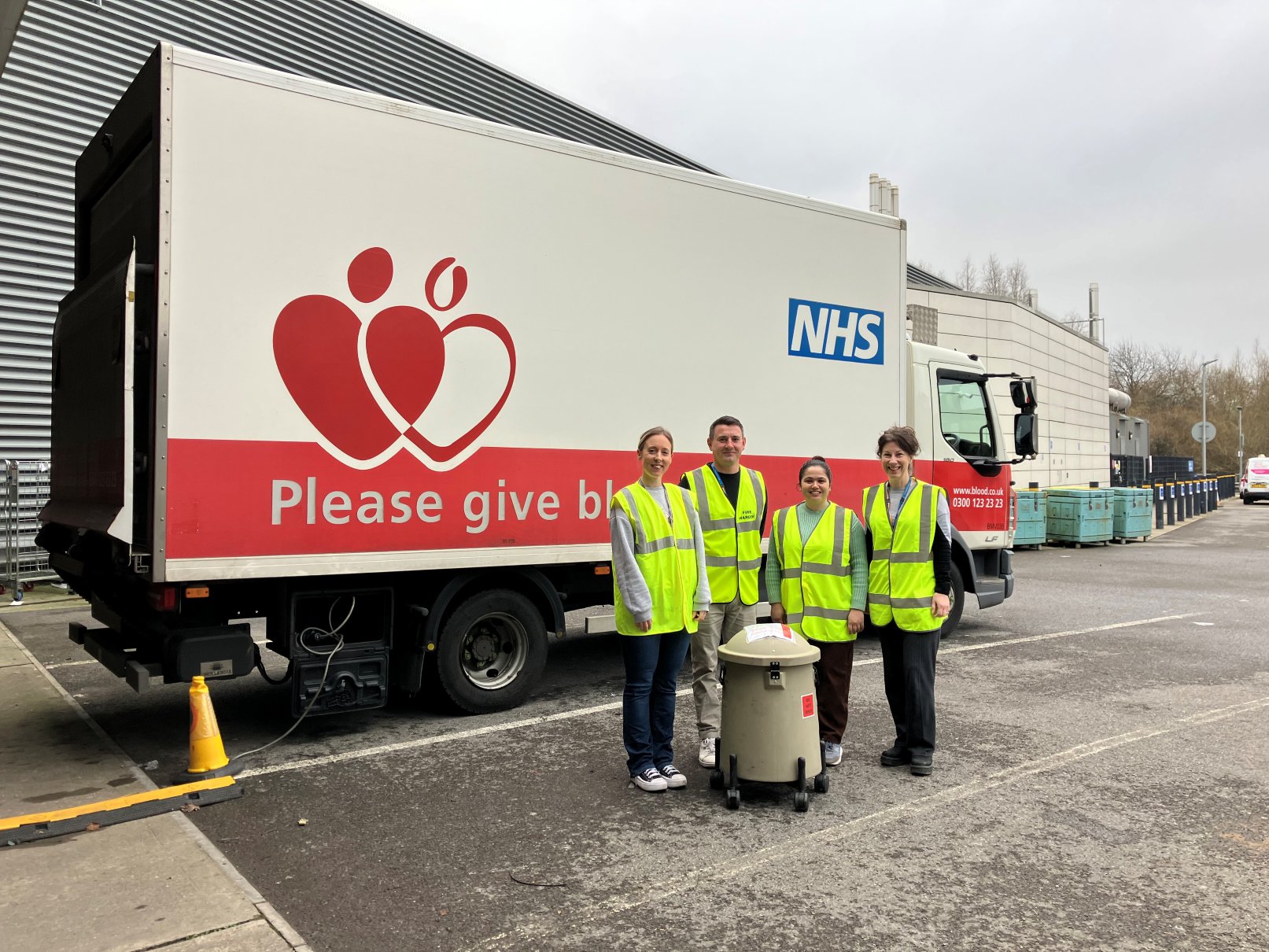 The NHS Cord Blood Team with a packed unit of cord blood, standing in front of a NHS Blood and Transplant blood delivery truck.