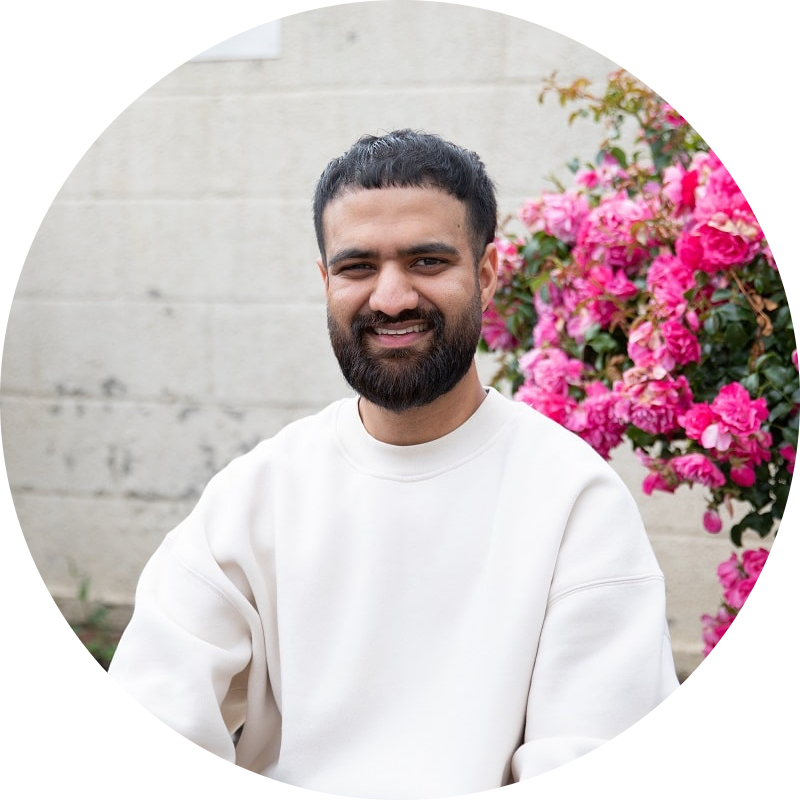 Stem cell donor Abrar sits next to a flower bed smiling at camera
