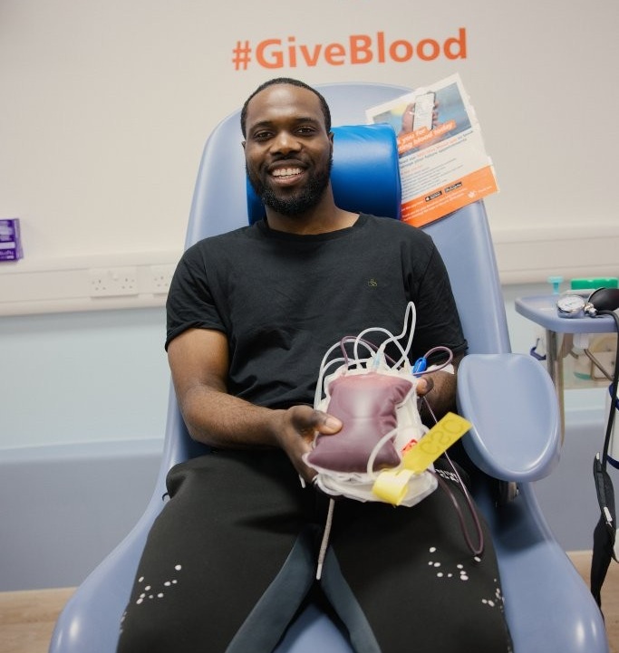Man  who doanted through a group booking sits in donation chair after giving blood holding his donation